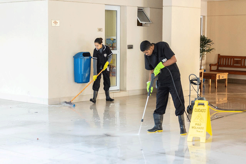 Profissional de limpeza realizando higienização em corredor de condomínio